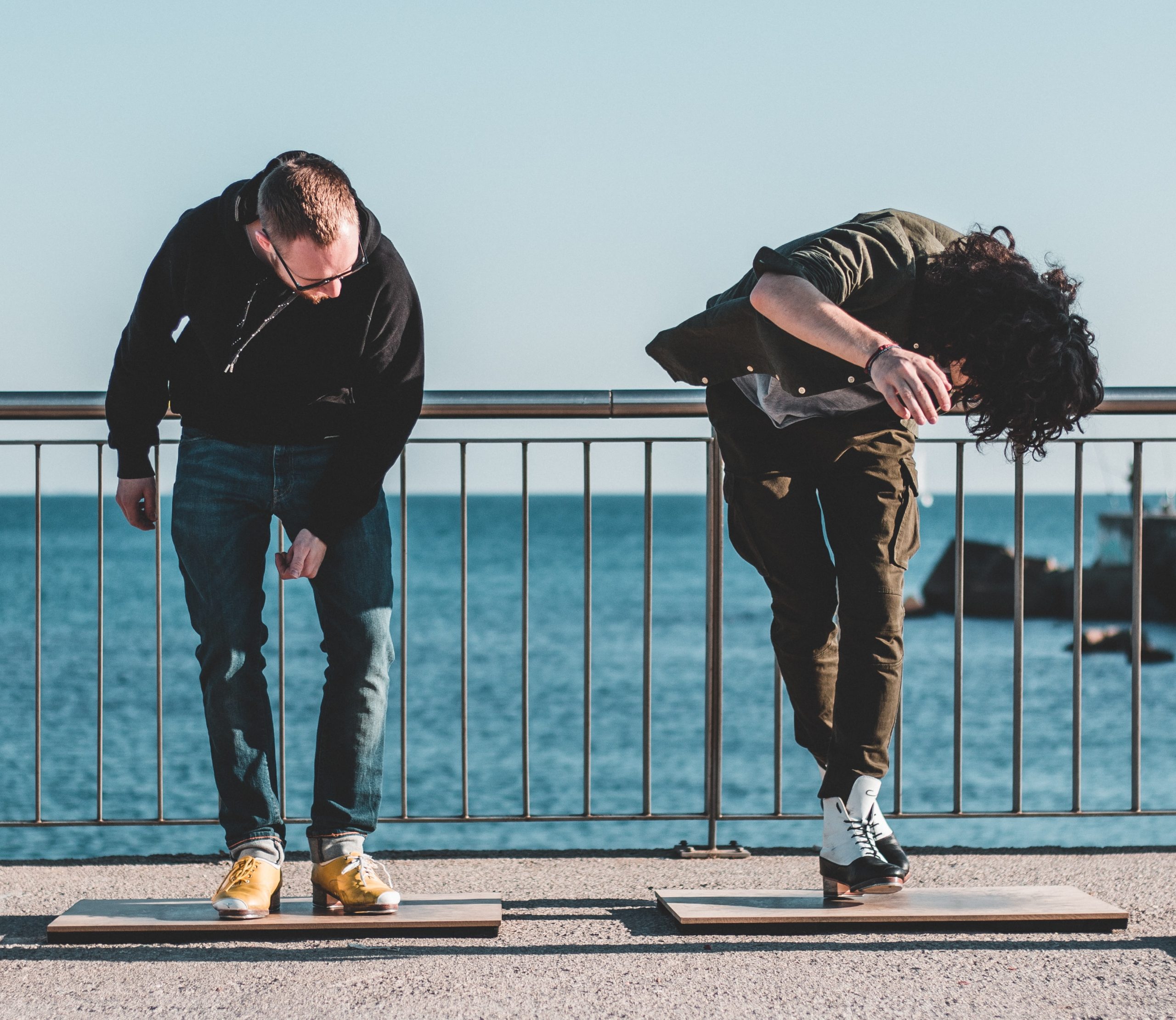 two men tapping outside on a boardwalk